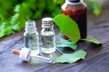 Pipette bottle, tincture and ginkgo leaves decorated on wooden background. Homeopathic concept.