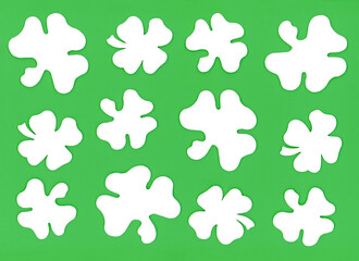 Saint Patrick's Day seamless pattern with three and four leaf clovers. White trefoil and quatrefoil leaves on green paper texture background. Shamrock symbol Irish lucky talisman.
