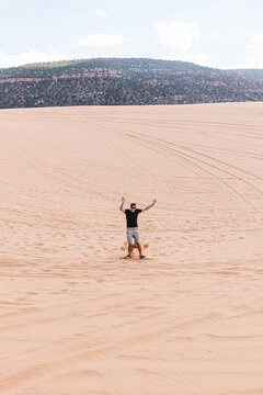 Man sandboarding on sand dune