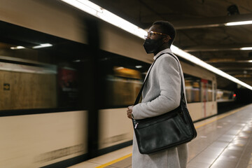 Black man in cloth mask on subway platform