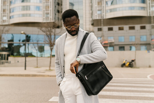 Stylish black man checking time on street