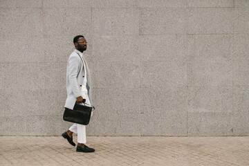 Stylish black man walking on paved street