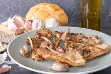 Dish of young goat ribs fried with garlic, a typical Spanish dish, on a wooden background.