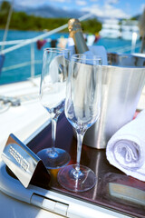 Romantic luxury evening on cruise yacht with champagne setting. Empty glasses and bottle with champagne and tropical sunset with sea background