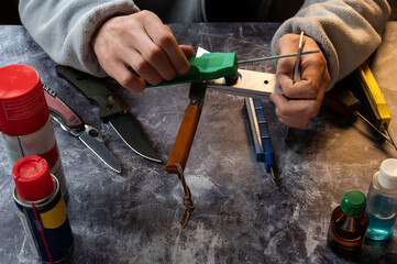 Manual sharpener of knives and tools. Sharpening a knife on a manual machine. The master sharpens the knife.