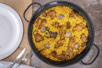 Top view of a rice paella with bush meat and snails.