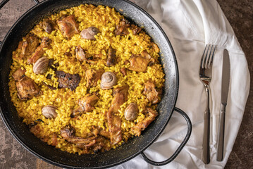 Top view of a rice paella with bush meat and snails.