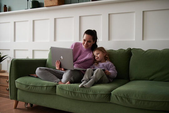 Mom working on laptop on couch, with daughter