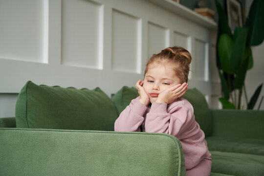 Cute little girl sitting in a chair looking bored
