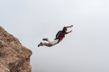 Thrill-seeker BASE jumping taking off from summit