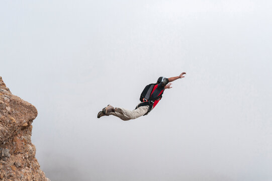 Thrill-seeker BASE jumping taking off from summit