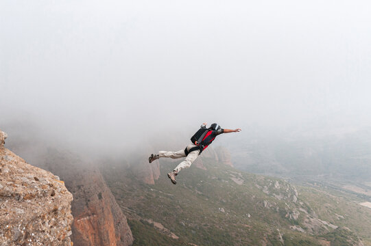 Thrill-seeker BASE jumping taking off from summit
