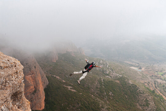 BASE jumper wearing parachute extiting from a cliff
