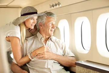 Keuken foto achterwand Oud vliegtuig Taking a luxury trip. Smiling senior couple on an airplane looking out the window.