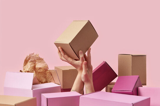 Woman's hand in pile with parcels holding brown box