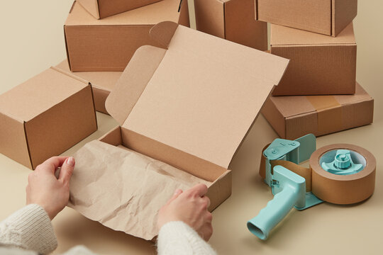 Woman using craft paper and scotch for packing parcels