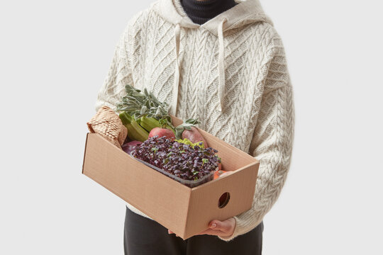 Female courier holding box with fresh vegetables