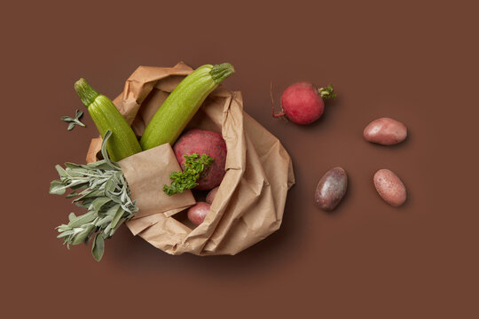 Paper bag with fresh vegetables over brown background