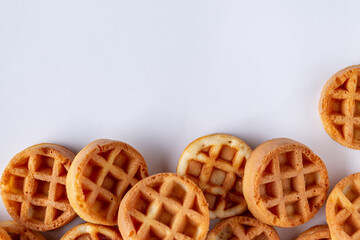 mini waffles scattered over white background, space for text