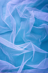 transparent tulle fabric arranged in soft folds on a green background, selective focus