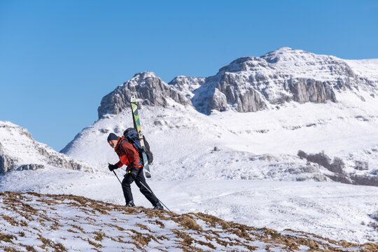 man carrying skis in backpack for back country skiing