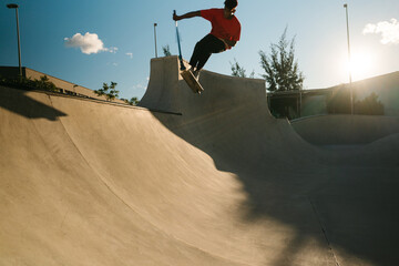 Young Latin American skater riding scooter on ramp