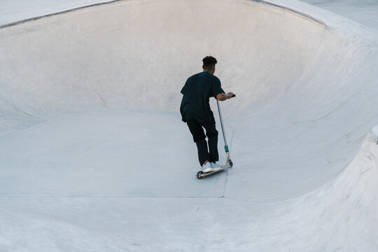 Man riding scooter on ramp in skate park