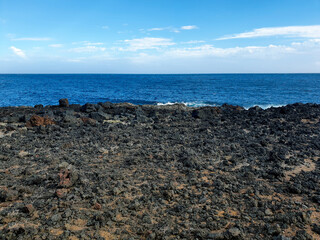 Volcanic shoreline with black rocks and blue ocean