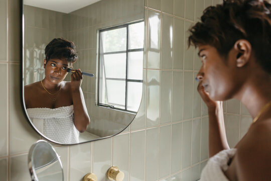 Young woman using a make up brush in the mirror