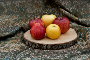 Five red and yellow apples are placed on a wooden board