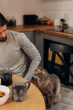 Faceless man with cat in kitchen