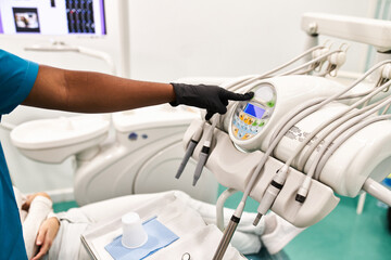 Crop dentist turning on dental machine