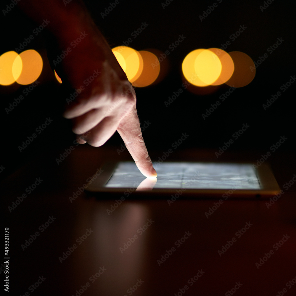 Poster putting in the late hours at work. closeup shot of a persons finger using a digital tablet in the da