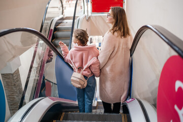 mom and daughter on escalator shopping day