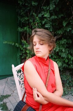 A tired young woman in a red dress sitting 