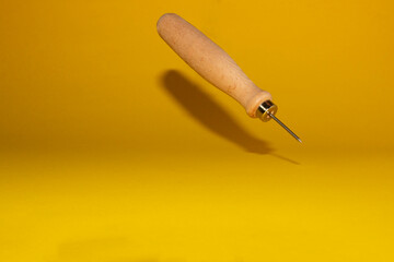 awl isolated on a yellow background with its shadow, work tools, copy space