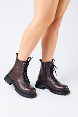 Women's brown spring boots made of genuine leather on a woman's leg. New collection of women's boots 2022