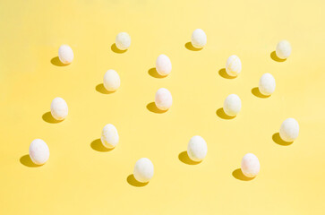 Easter eggs chaotic pattern on yellow color background. Happy Easter concept. A simple minimalist flat lying top view.