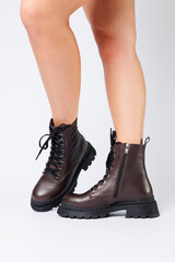 Women's brown spring boots made of genuine leather on a woman's leg. New collection of women's boots 2022
