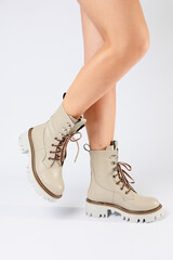 Women's white spring boots made of genuine leather are worn on a woman's leg. New collection of women's boots 2022