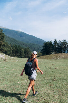 Content female traveler walking on meadow while hiking