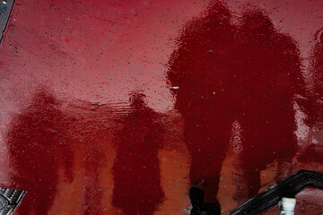 Reflection of human figures on the surface of wet asphalt.