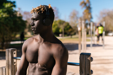 African guy listening to music on sports ground