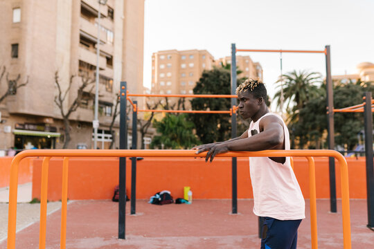 Black sportsman preparing for workout on parallel bars