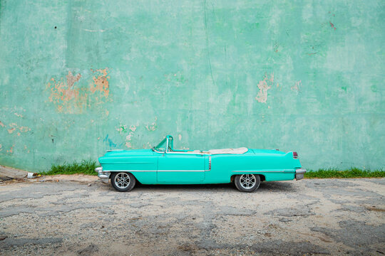 old aqua colored car parked in front of a wall