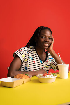 Smiling woman with sald and burger in studio