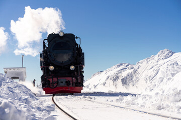 Historische Dampflokomotive im Schnee mit Dampf auf dem Brocken in Deutschland