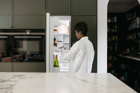 Young Woman Getting A Bowl Of Fruit Out Of The Fridge