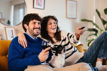 Merry couple with dog watching TV together