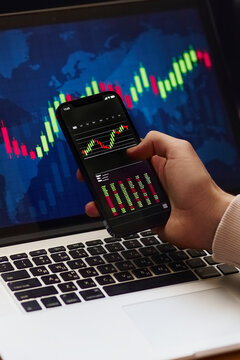 Businessman investor analyst using mobile phone analytics to analyze crypto currency financial market, trade data index chart graph on smartphone and laptop screen. close-up